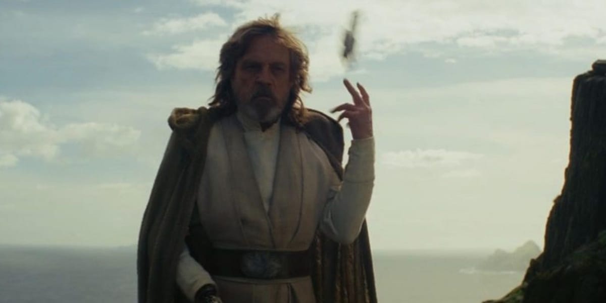 A wide shot of Luke Skywalker standing on a grassy cliff, tossing a legacy lightsaber over his shoulder.